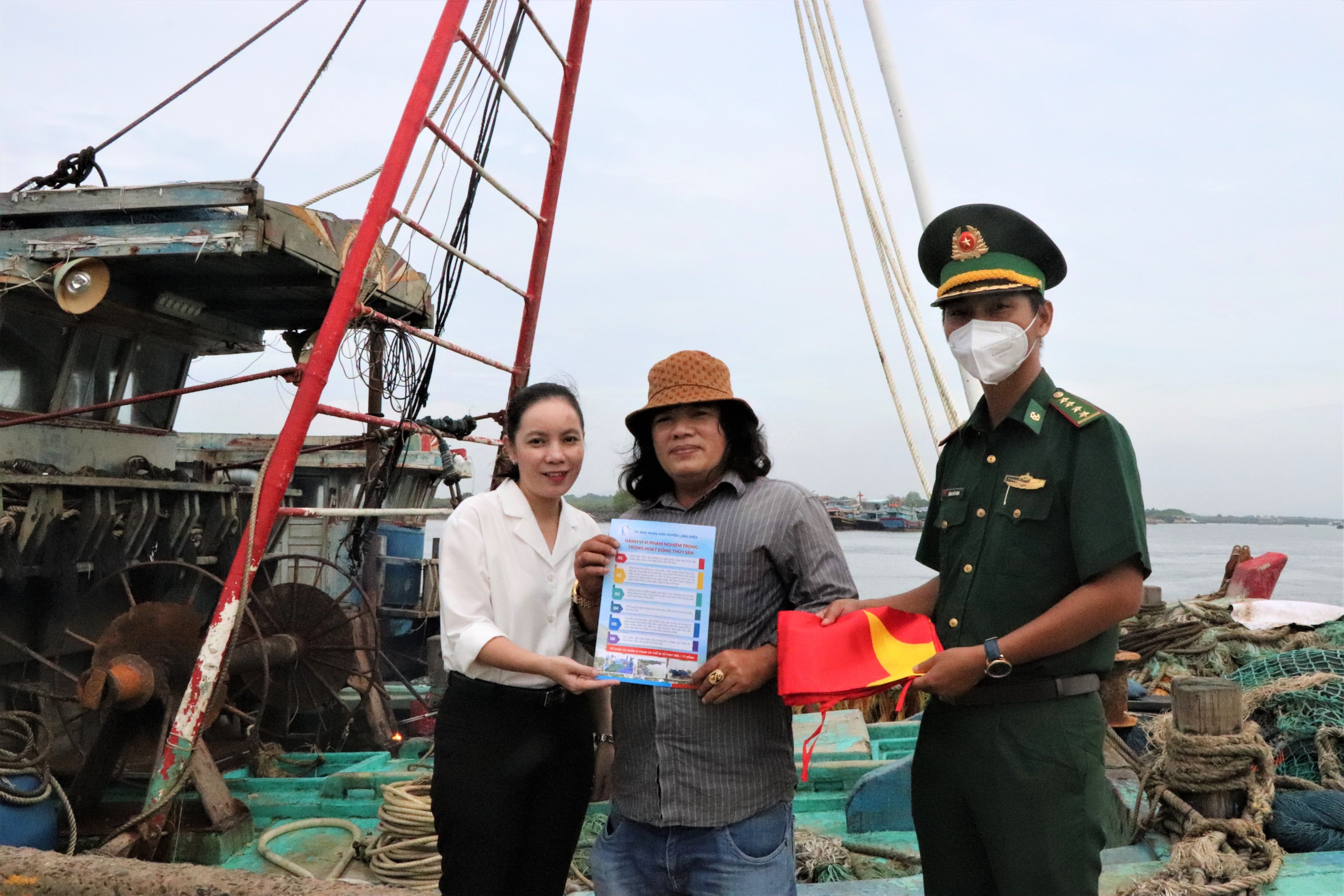 Bà Lê Thị Ngọc Hạnh, Trưởng Ban Tuyên giáo Huyện ủy Long Điền trao tờ rơi tuyên truyền các quy định xử lý vi phạm đối với hoạt động khai thác hải sản trên biển cho ngư dân tại cảng cá Hưng Thái (xã Phước Hưng, huyện Long Điền).