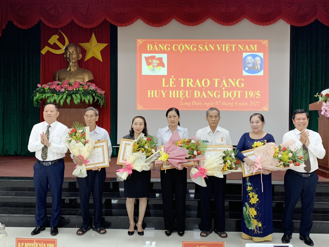 Ông Nguyễn Văn Xinh và ông Lê Ngọc Linh trao Huy hiệu và tặng hoa chúc mừng các đảng viên và gia đình có đảng viên 55 và 50 năm tuổi Đảng.