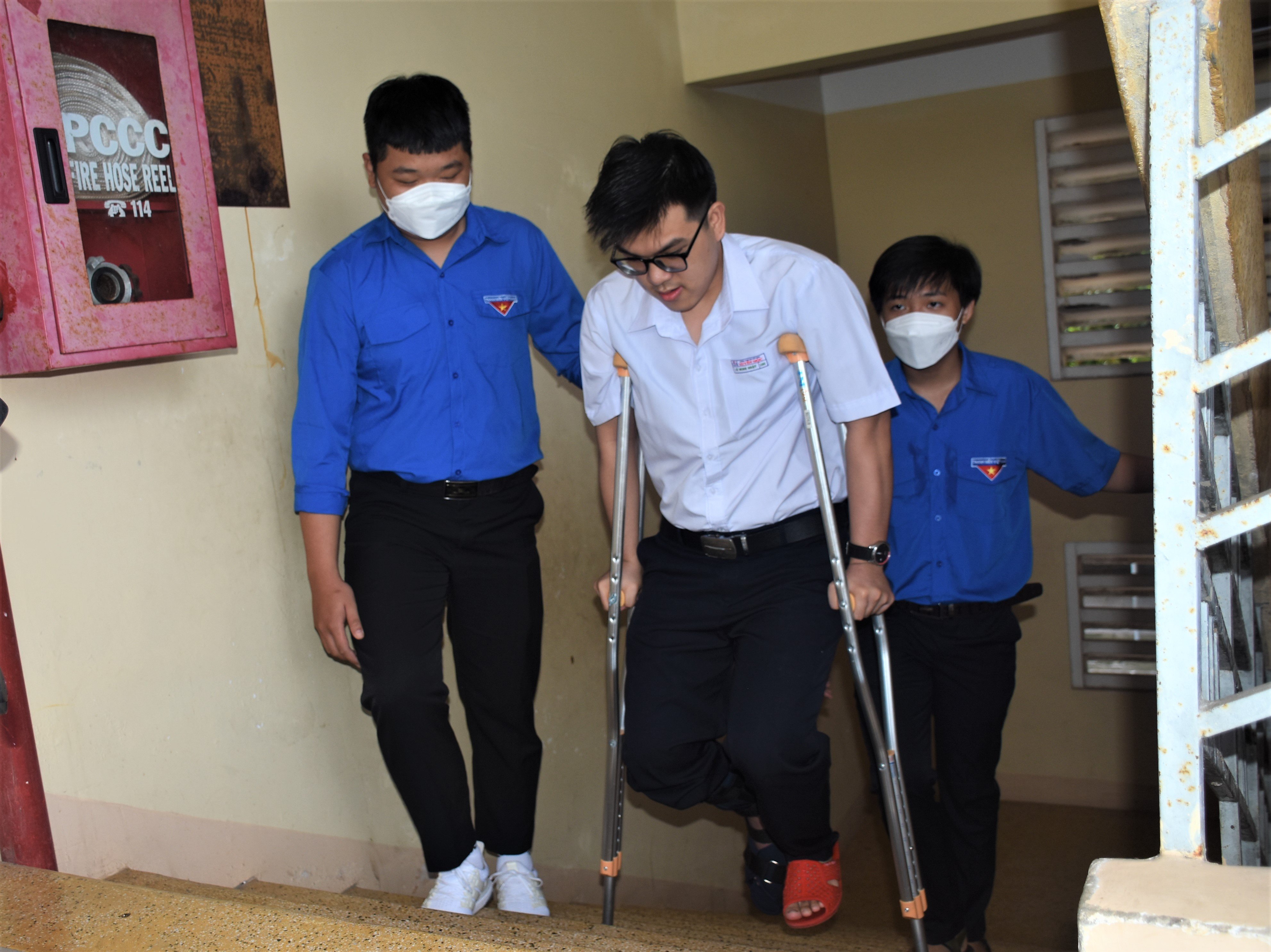 TS Lê Minh Nhật, HS lớp 12A1 Trường THPT Xuyên Mộc bị gãy chân được các tình nguyện viên hỗ trợ di chuyển lên phòng thi tại lầu 3 điểm thi Trường THPT Xuyên Mộc. Ảnh: NGỌC BÍCH