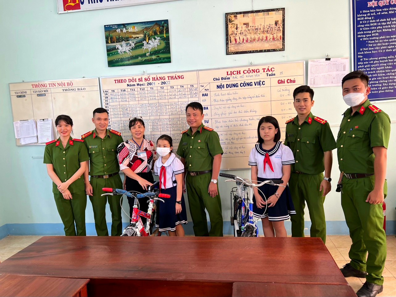 Thiếu tá Lê Hòa Hợp (bìa phải) cùng các đồng nghiệp trao tặng xe đạp cho học sinh nghèo trên địa bàn.