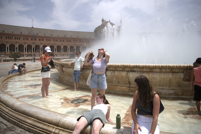 Người dân giải nhiệt tại đài phun nước ở Seville, Tây Ban Nha.