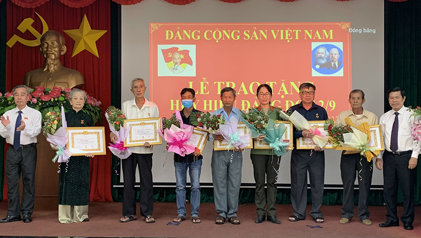 Ông Nguyễn Văn Xinh, Ủy viên Ban Thường vụ Tỉnh ủy, Trưởng Ban Tuyên giáo Tỉnh ủy (bìa phải) và ông Võ Hữu Hạnh, Phó Bí thư Thường trực Huyện ủy Long Điền (bìa trái) trao Huy hiệu và tặng hoa chúc mừng các đảng viên, gia đình có đảng viên 55 và 50 năm tuổi Đảng. Ảnh: NGUYỄN TUYỀN