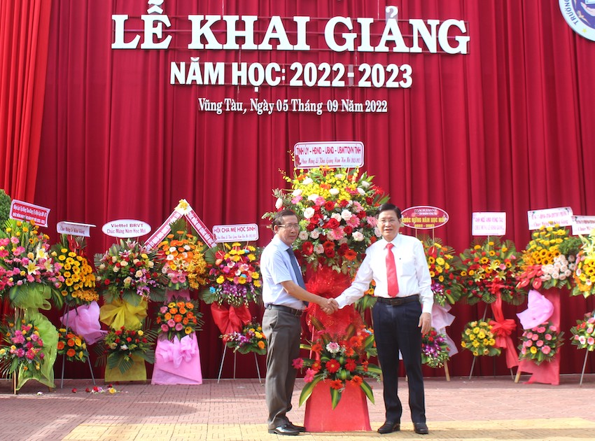 Ông Lê Ngọc Khánh, Phó Chủ tịch UBND tỉnh tặng lẵng hoa tươi thắm của Tỉnh ủy, HĐND, UBND, UBMTTQVN tỉnh cho ban giám hiệu Trường THPT Nguyễn Huệ. Ảnh: HỒNG PHƯƠNG.