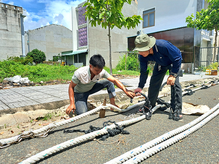 Ông Nguyễn Văn Nhỏ (bìa phải) hướng dẫn thợ làm dây kéo lưới chuẩn bị cho tàu cá ra khơi đánh bắt.