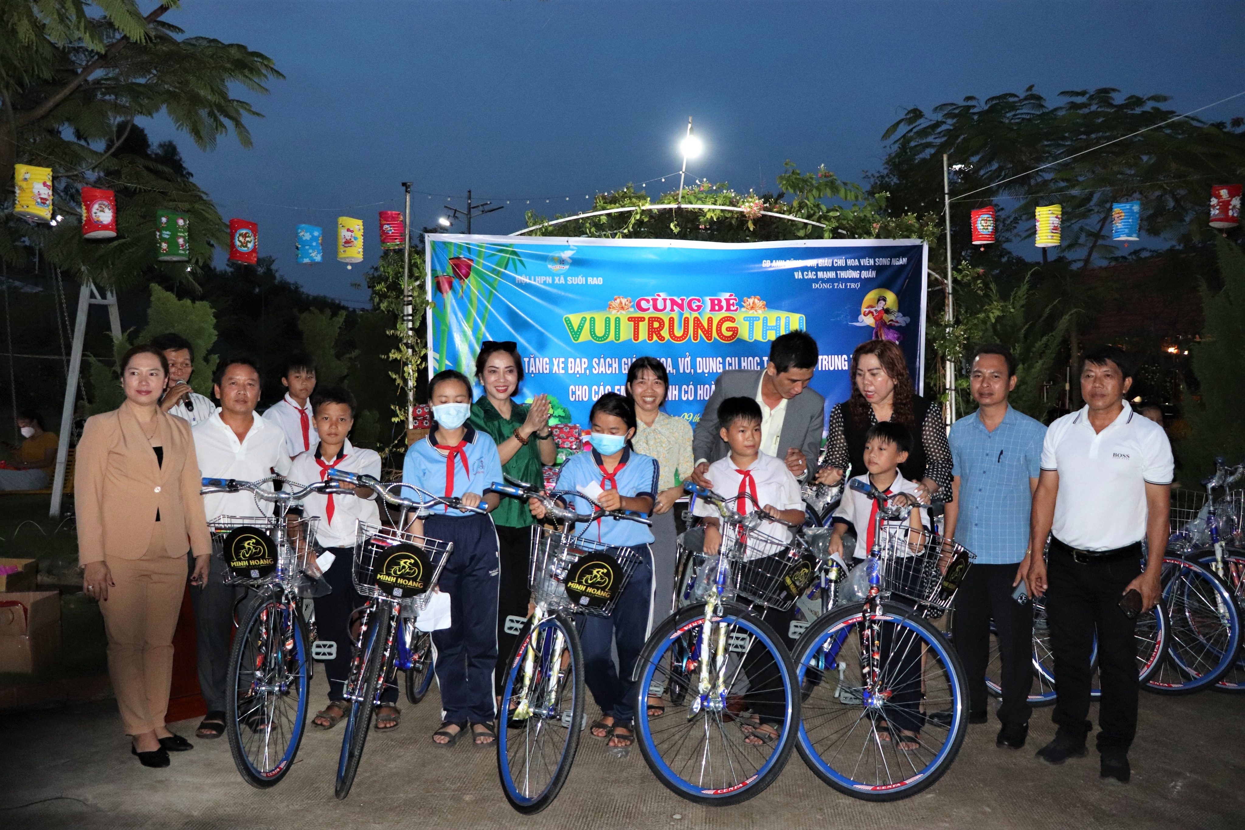 Bà Nguyễn Thị Ngọc Giàu (bên trái), chủ Hoa viên Song Ngân và các mạnh thường quân trao tặng xe đạp cho HS nghèo vượt khó trên địa bàn xã Suối Rao.