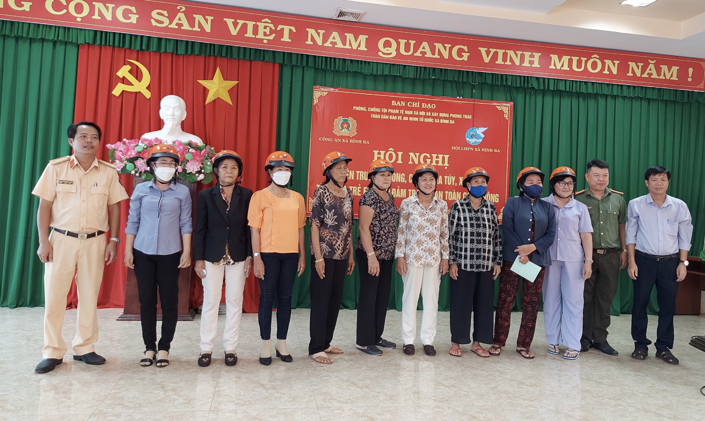Trung tá Nguyễn Minh Hoàng (bên trái), cán bộ Đội Cảnh sát giao thông-Trật tự Công an huyện Châu Đức trao tặng mũ bảo hiểm cho các đại biểu dự hội nghị tuyên truyền.