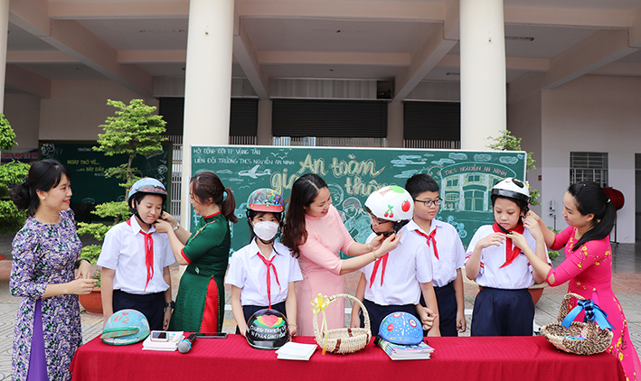Cô và trò Trường THCS Nguyễn An Ninh bên những chiếc mũ bảo hiểm đã được trang trí.