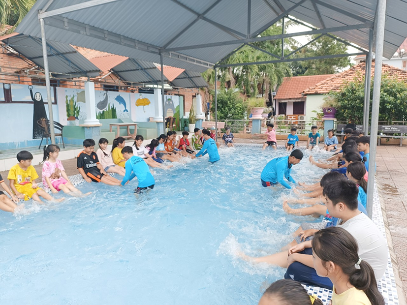 Hướng dẫn các em học sinh thực hành bơi lội.