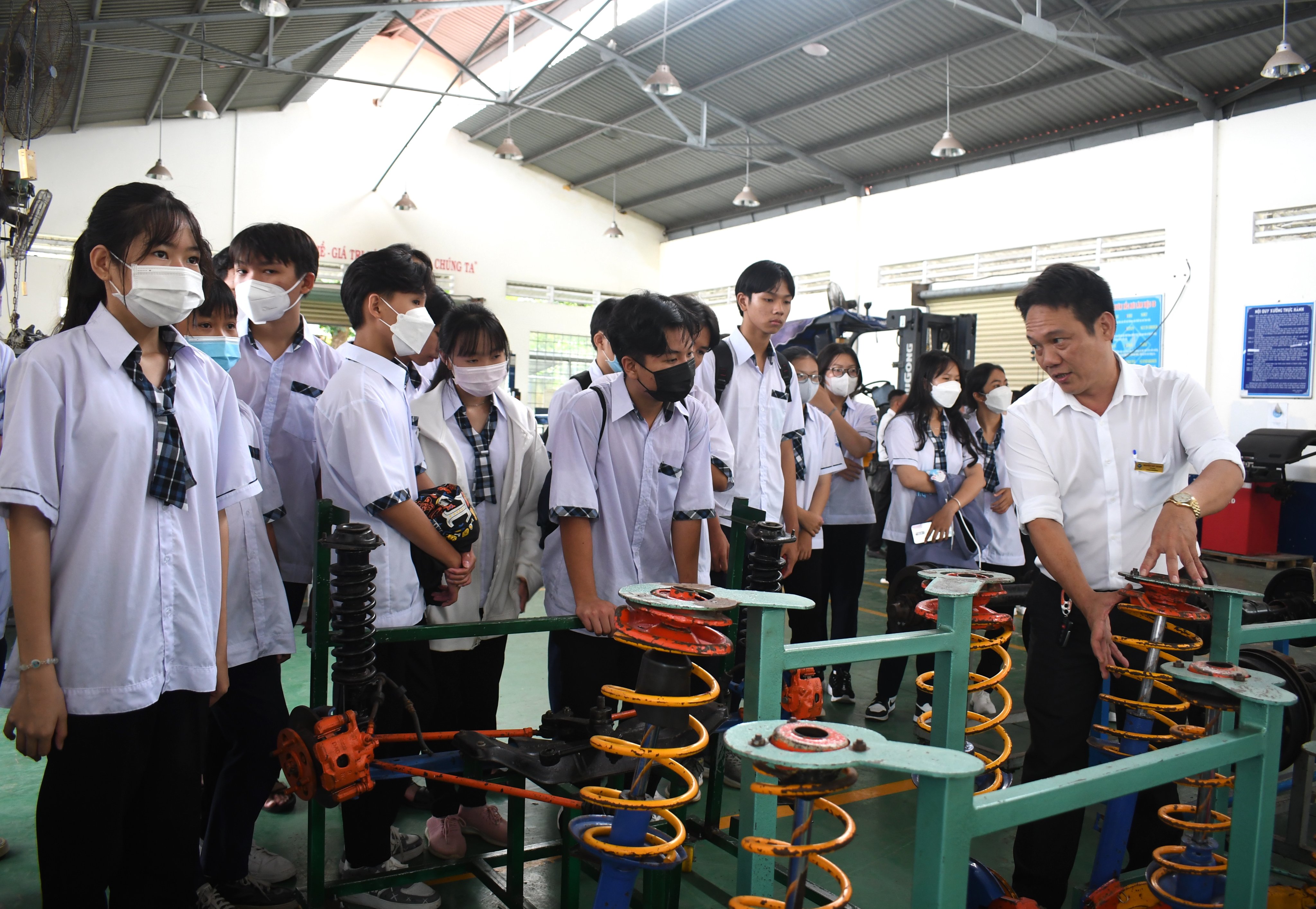 Các em HS Trường THPT Võ Thị Sáu và Phổ thông Dân tộc Nội trú tỉnh nghe giảng viên Trường CĐ Kỹ thuật Công nghệ Bà Rịa-Vũng Tàu giới thiệu về các loại máy tại xưởng Cơ khí. Ảnh: HUYỀN TRANG