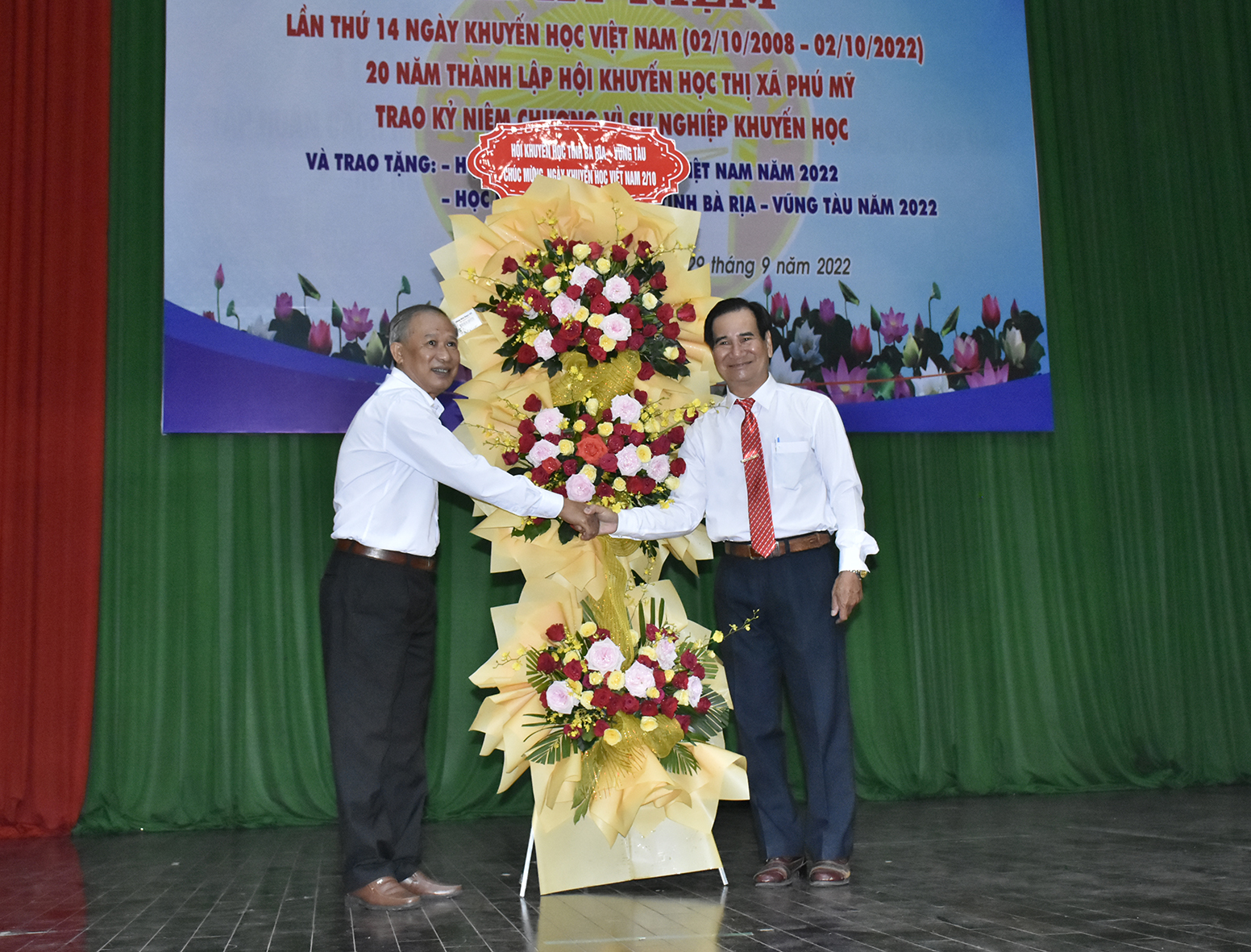 Ông Lương Đức Đích (bên trái), Chủ tịch Hội Khuyến học tỉnh tặng hoa chúc mừng 20 năm thành lập Hội Khuyến học TX.Phú Mỹ.