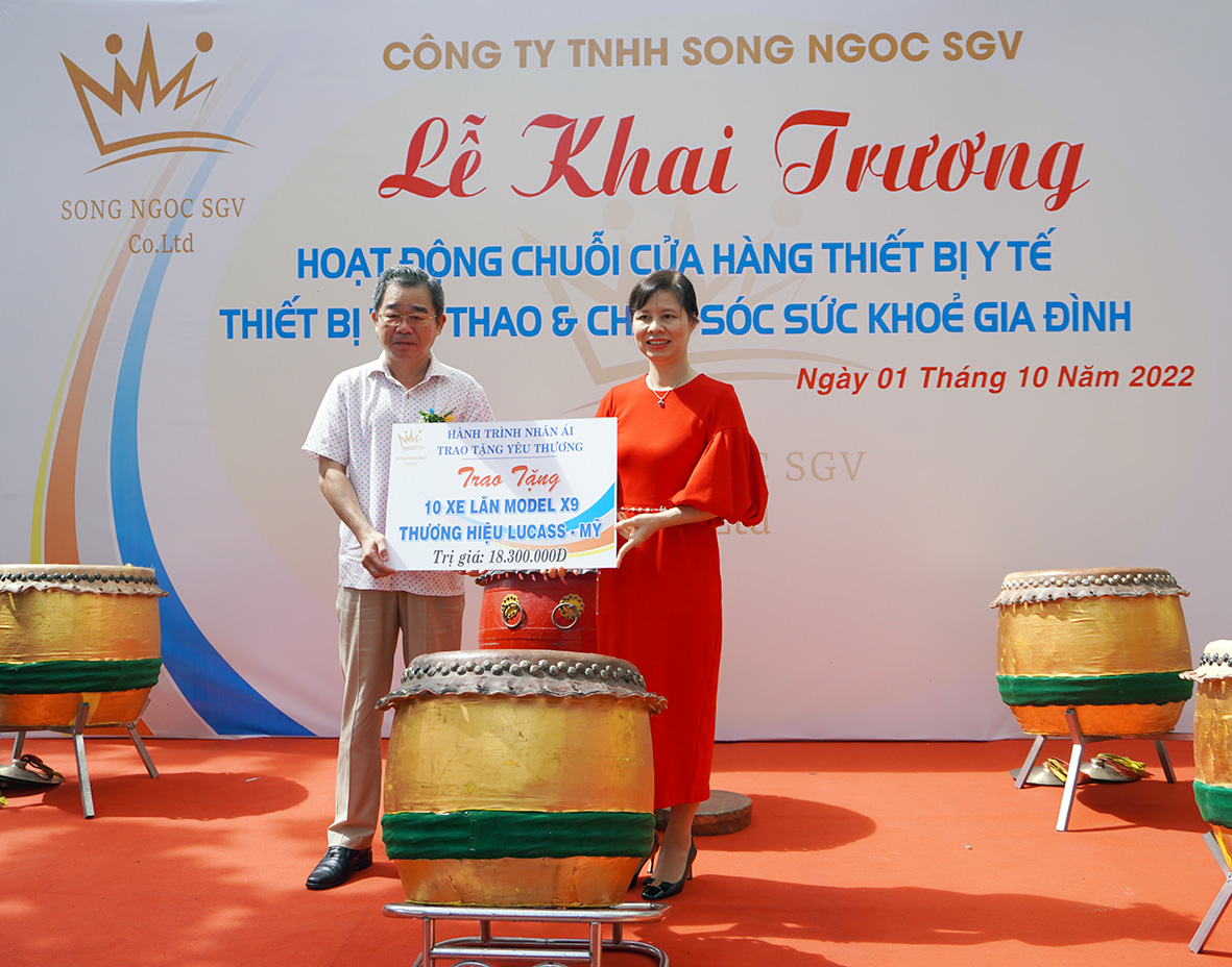 Bà Trần Thị Ngọc Lan, Giám đốc Công ty Song Ngọc SGV trao tặng bảng tượng trưng 10 xe lăn cho ông Lê Văn Hậu, Chủ tịch Hội Chữ thập đỏ tỉnh.