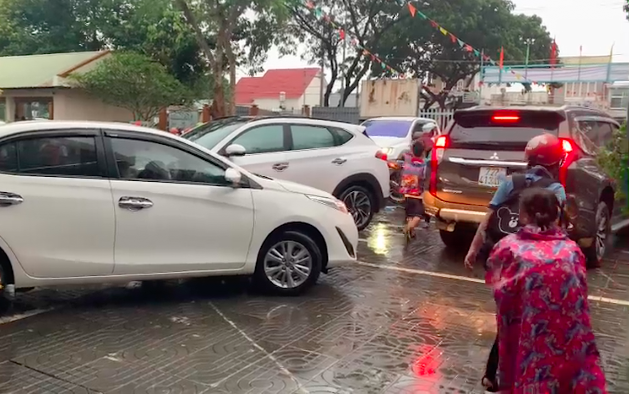 Học sinh phải luồn lách giữa hàng xe ô tô trên sân trường tiềm ẩn nguy cơ tai nạn giao thông - ảnh cắt từ clip PHHS cung cấp.