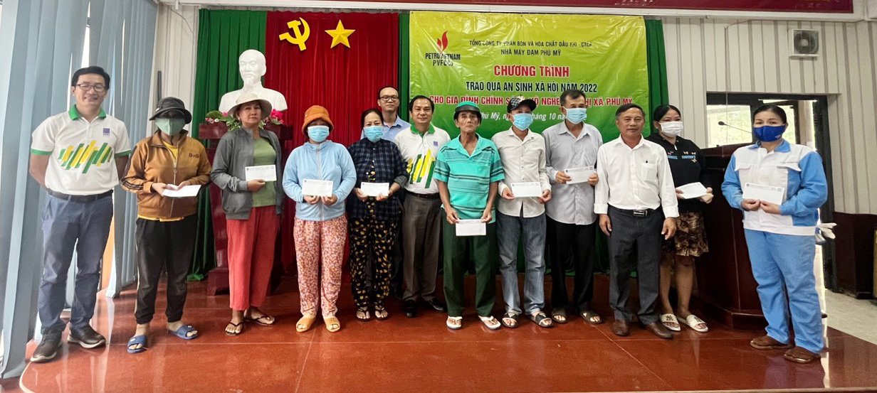Đại diện MTTQ thị xã và Tổng Công ty Phân bón và Hóa chất Dầu khí trao quà đến các hộ nghèo.