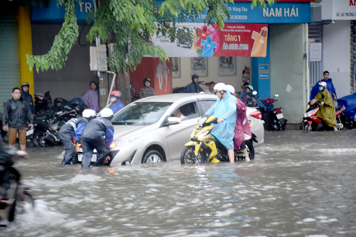 Công nhân thoát nước hỗ trợ người dân đẩy xe bị chết máy trên đường Trương Công Định.