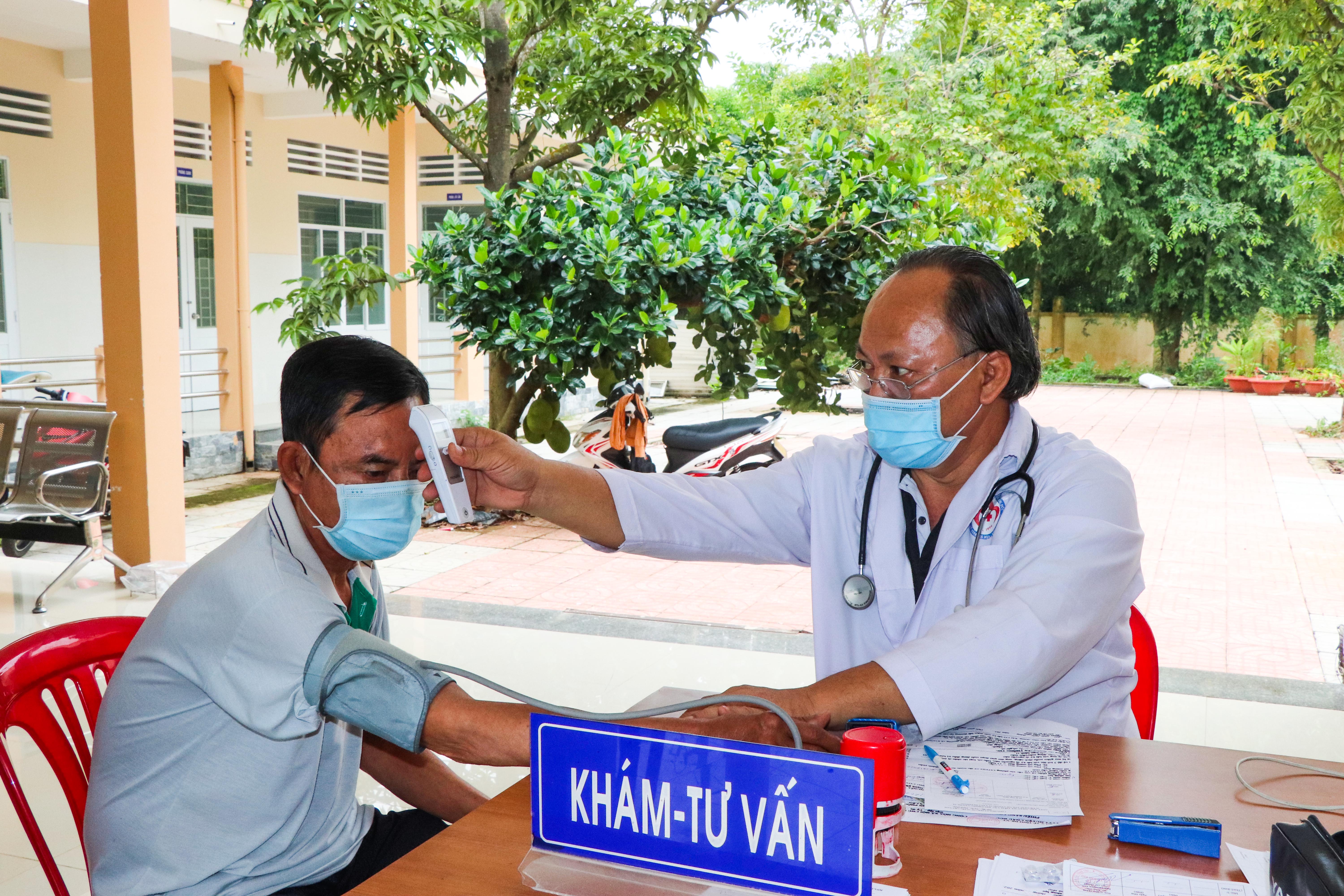 Bác sĩ Lê Quang Phước, Trưởng Trạm Y tế xã Suối Rao, đo thân nhiệt, khám sàng lọc cho người dân trước khi tiêm vắc xin phòng COVID-19.
