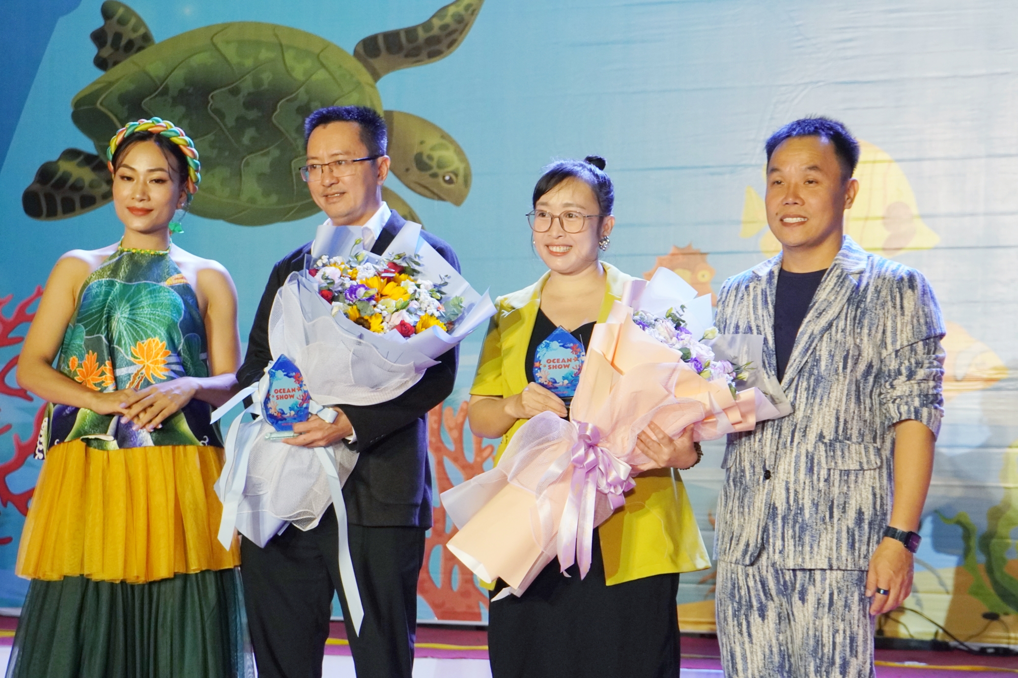 Nhà thiết kế Việt Hùng (bên phải) tặng hoa cảm ơn các đơn vị đồng hành với chương trình.