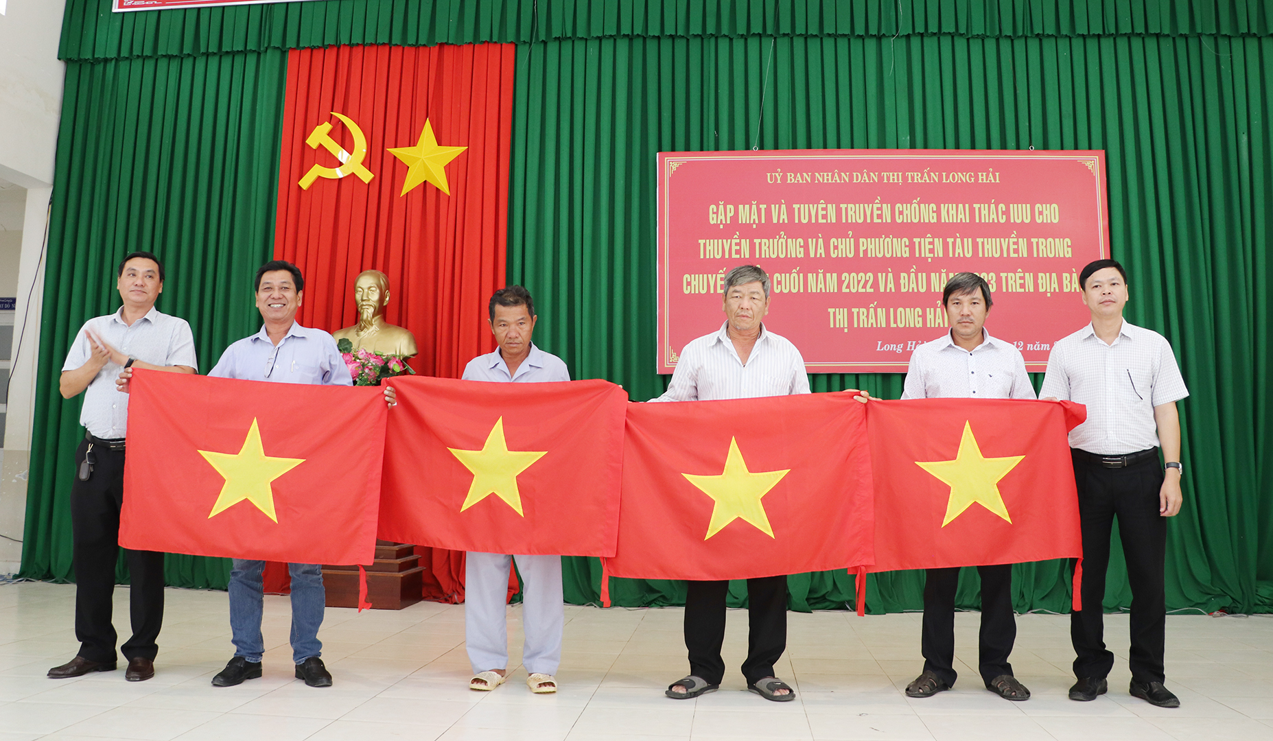 Các ông Ngô Thanh Phúc, Bí thư Đảng ủy Thị trấn; Trần Quốc Nhẫn, Phó Chủ tịch UBND thị trấn trao cờ Tổ quốc đến các thuyền trưởng, chủ phương tiện tàu cá.