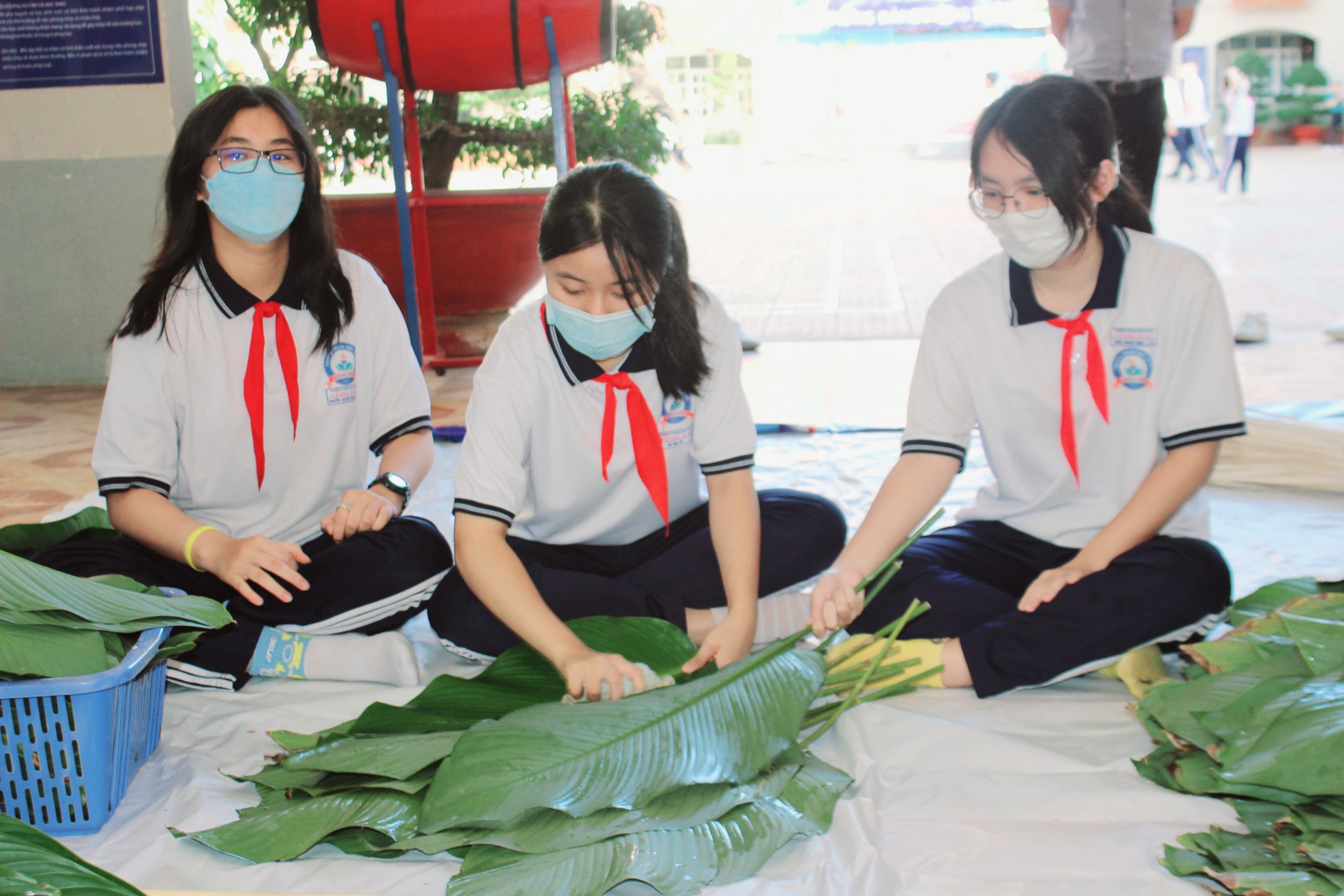 Các em HS tỉ mỉ lau khô từng chiếc lá dong để gói bánh.