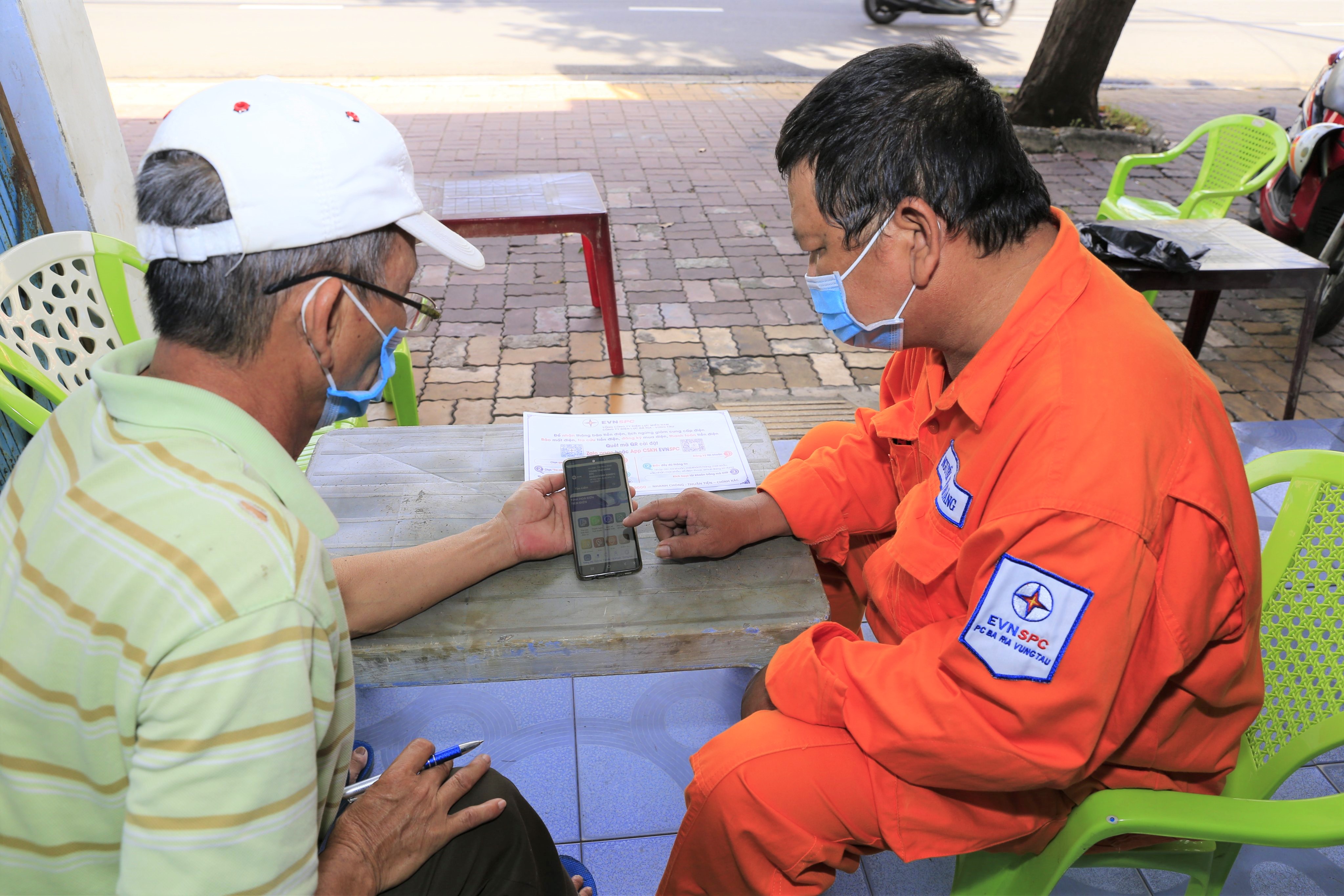 Nhân viên điện lực hướng dẫn khách hàng cài đặt và sử dụng aap thanh toán tiền điện.