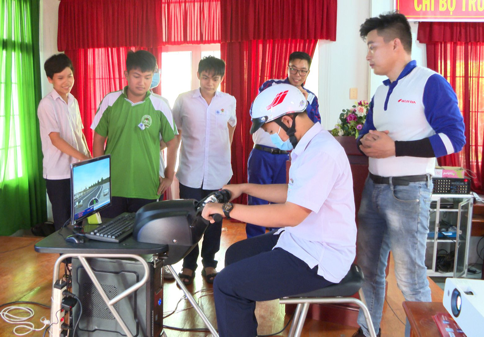 Kỹ thuật viên Công ty TNHH Honda Nghĩa 4 hướng dẫn tư thế ngồi lái xe an toàn và đội mũ bảo hiểm đúng cách cho học sinh.