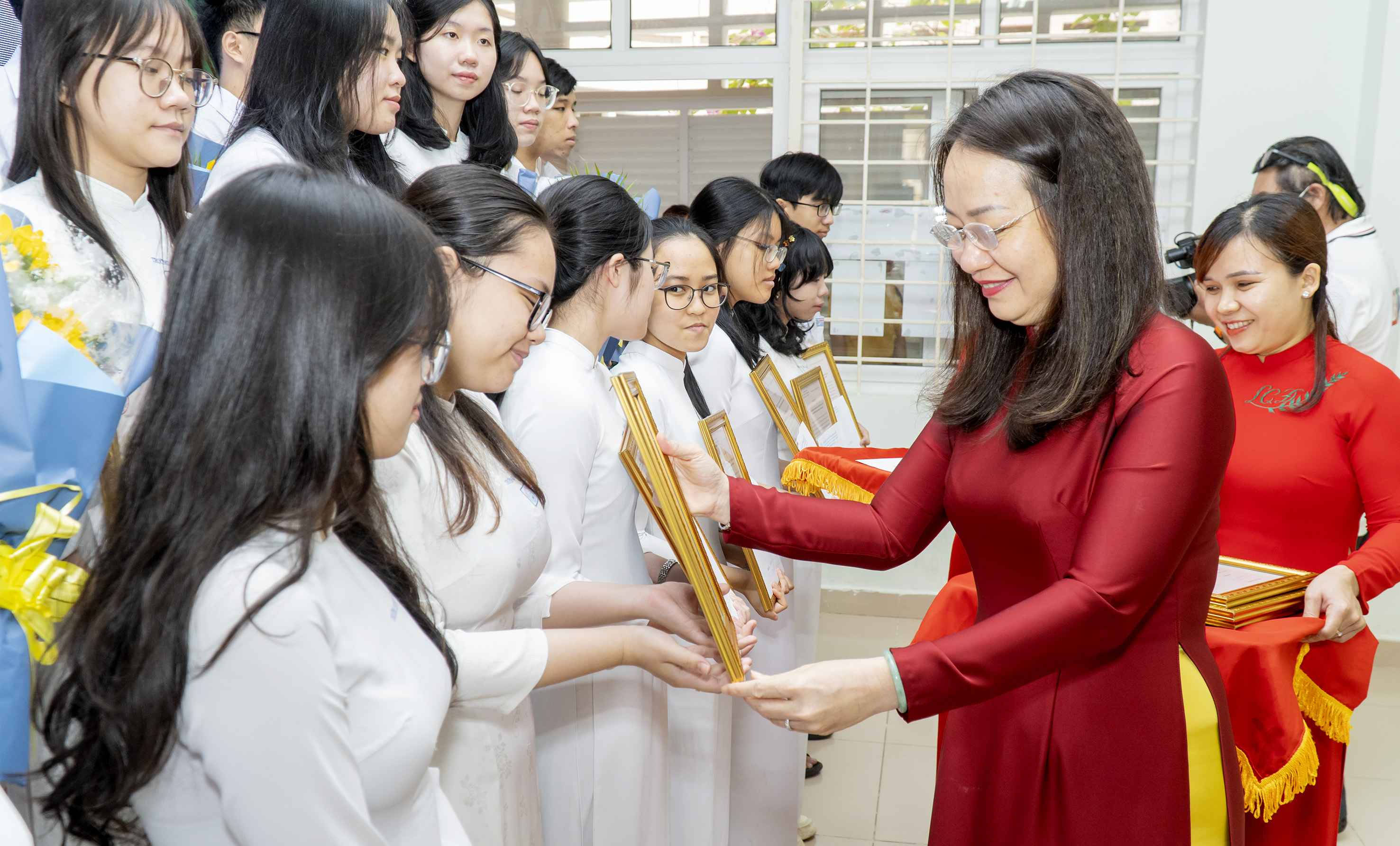 Bà Trần Thị Ngọc Châu, Giám đốc Sở GD-ĐT trao thư khen của Chủ tịch UBND tỉnh và tặng hoa động viên các HS.