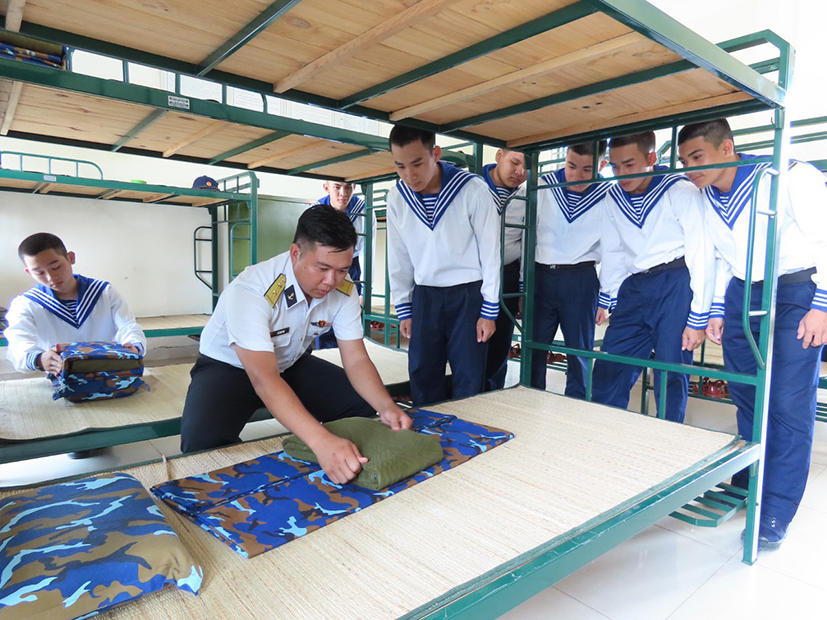 Cán bộ Trung tâm Huấn luyện Vùng 2 Hải quân hướng dẫn chiến sĩ mới gấp chăn màn.
