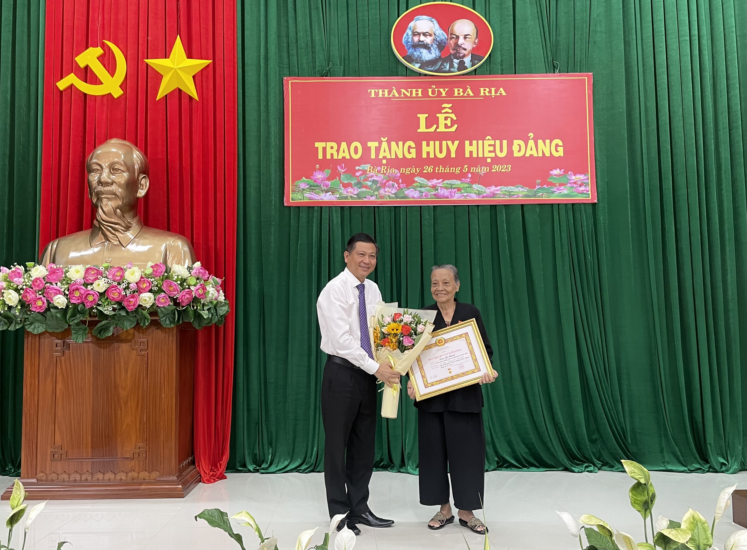 Ông Trần Văn Tuấn, Ủy viên Ban Thường vụ Tỉnh uỷ, Bí thư Thành ủy Bà Rịa trao Huy hiệu 65 năm tuổi Đảng cho đảng viên Đoàn Thị Khanh, sinh hoạt tại chi bộ khu phố 4, Đảng bộ phường Phước Nguyên.