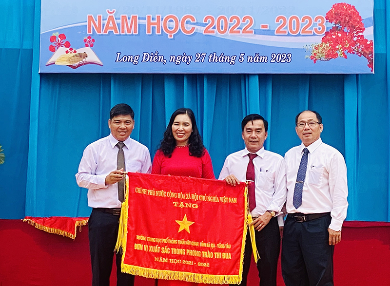 Đại diện Sở Nội vụ và Sở Giáo dục- Đào tạo tỉnh (bên phải) thừa ủy quyền của Thủ tướng Chính phủ trao Cờ thi đua của Thủ tướng Chính phủ cho Ban giám hiệu Trường THPT Trần Văn Quan.