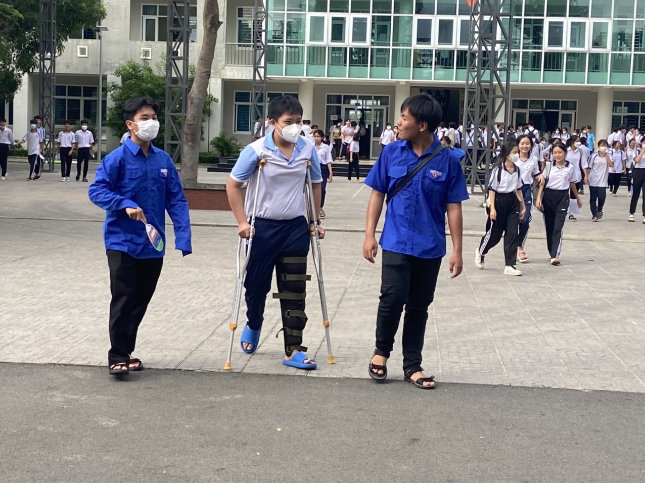 Các tình nguyện viên hỗ trợ 1 thí sinh bị thương khó khăn đi lại tại điểm thi THPT Võ Thị Sáu, huyện Đất Đỏ