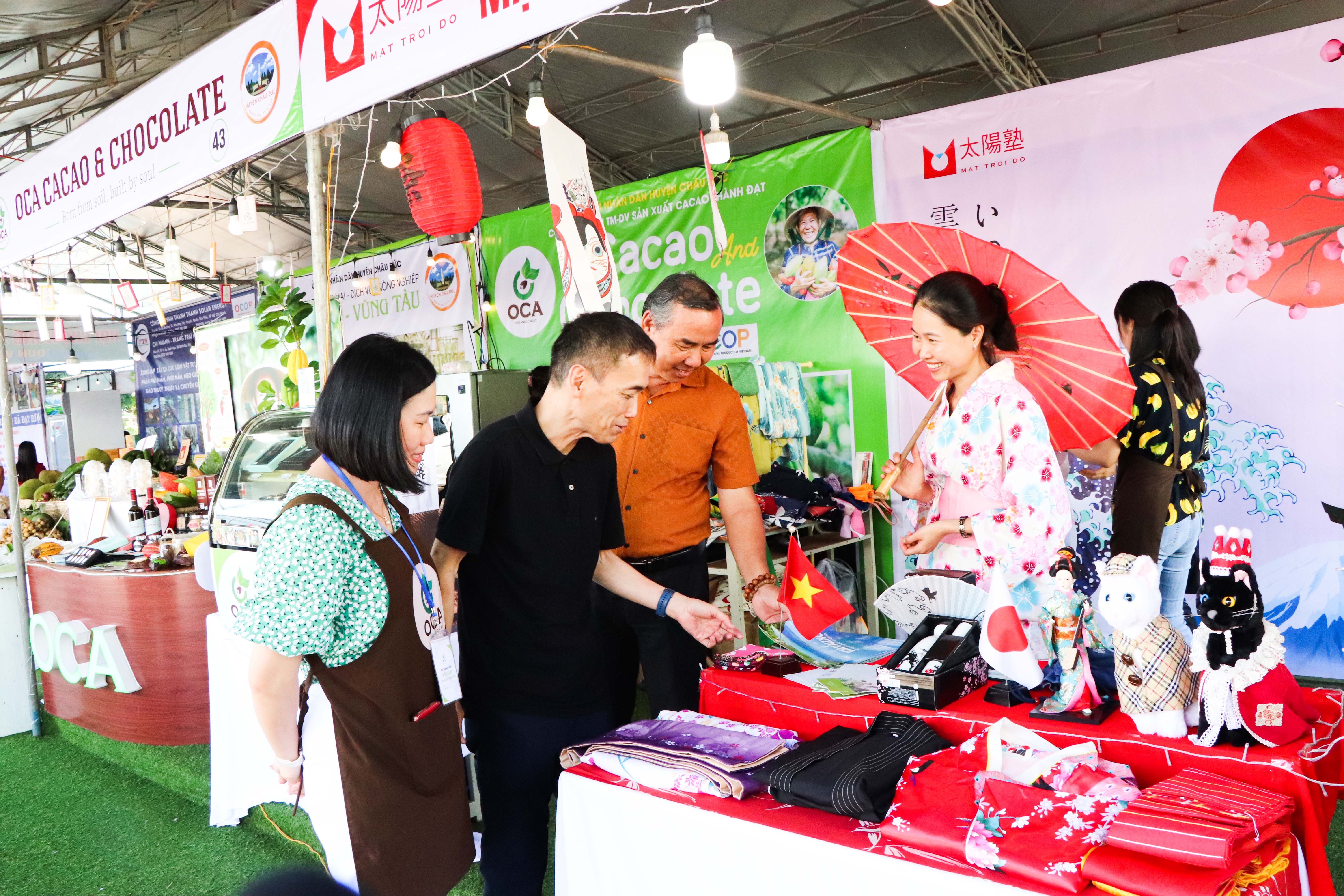 Ông Hiroki Nozawa (thứ 2 từ trái vào), Tổng Giám đốc Công ty OCA JAPAN tham quan gian hàng giới thiệu các sản phẩm chế biến từ hạt ca cao và văn hóa Nhật Bản tại Việt Nam.