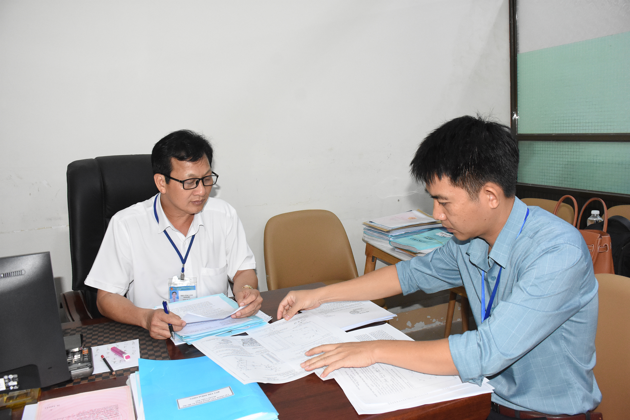 Ông Thái Tăng Lâm, Giám đốc Chi nhánh VPĐKĐĐ huyện Châu Đức (trái) nghe nhân viên báo cáo các hồ sơ cấp đổi GCNQSDĐ vướng mắc chưa xử lý được.