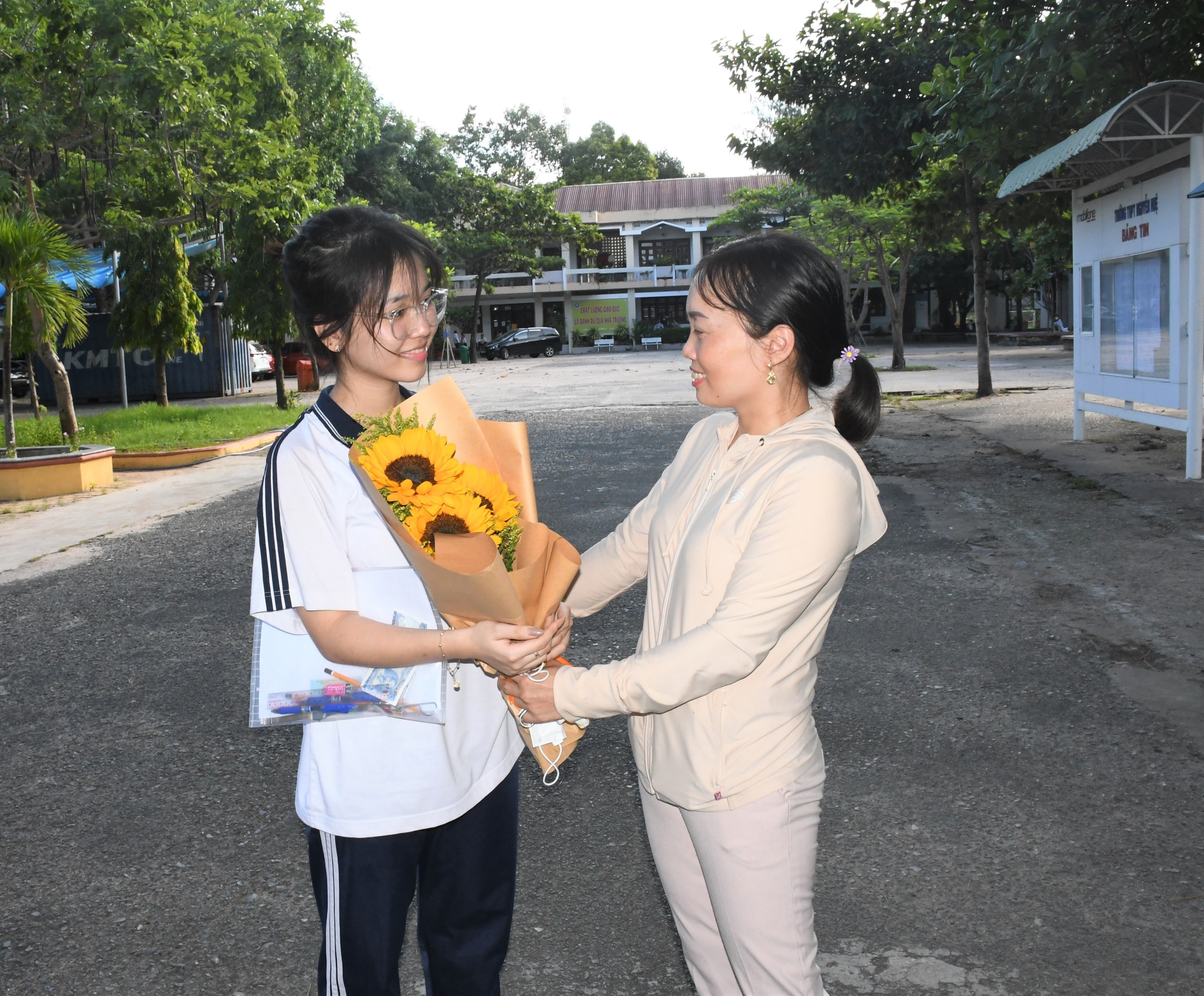 Một phụ huynh tặng hoa chúc mừng con gái sau khi hoàn thành các môn thi trong kỳ thi THPT năm 2023 tại điểm thi THPT Nguyễn Huệ