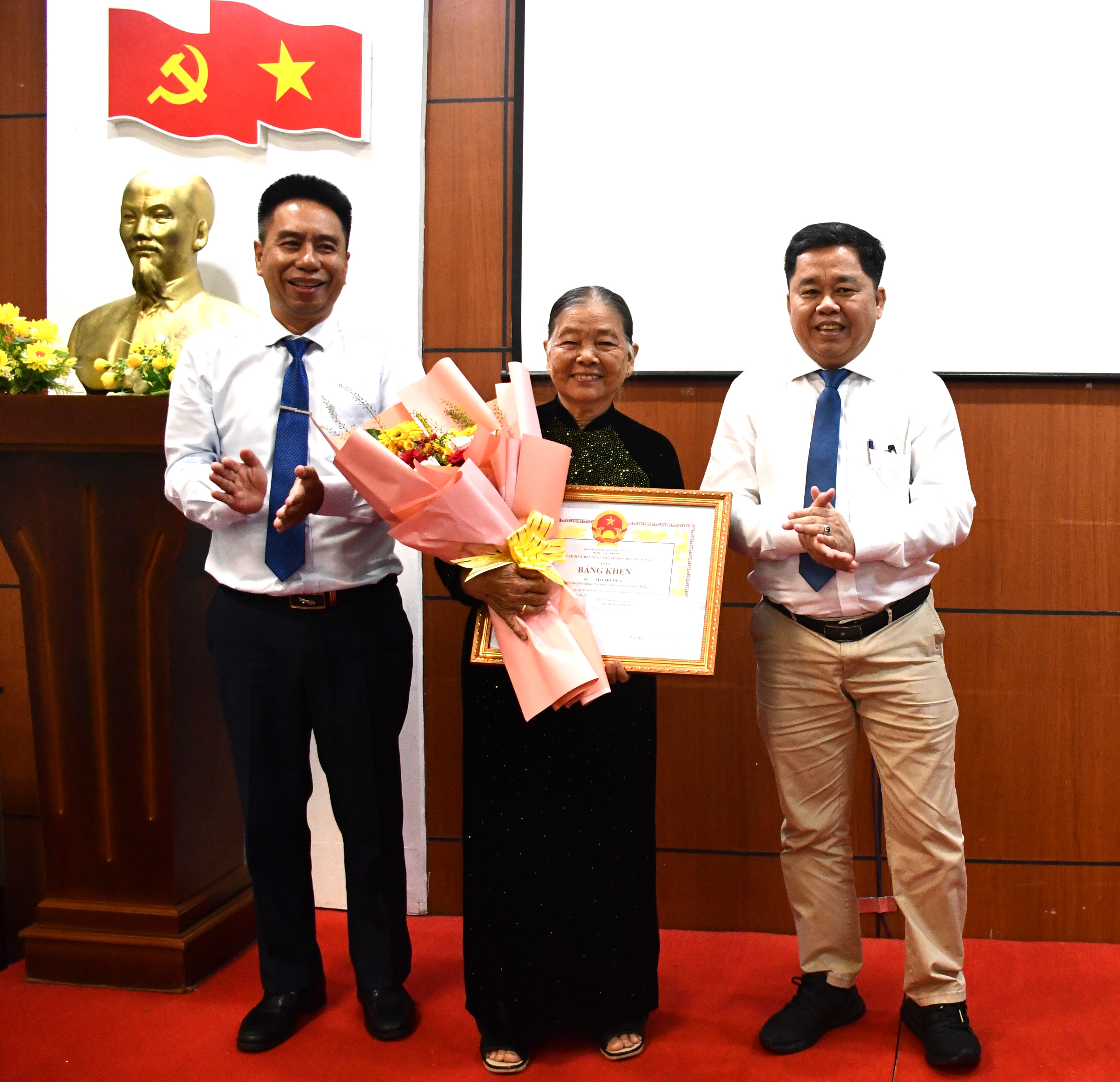 Bác sĩ Trần Ngọc Triệu, Phó Giám đốc Sở Y tế (bên phải) và bác sĩ Nguyễn Viết Giáp, Giám đốc Bệnh viện Mắt tỉnh  tặng Bằng khen của UBND tỉnh cho bà Mai Thị Mười.