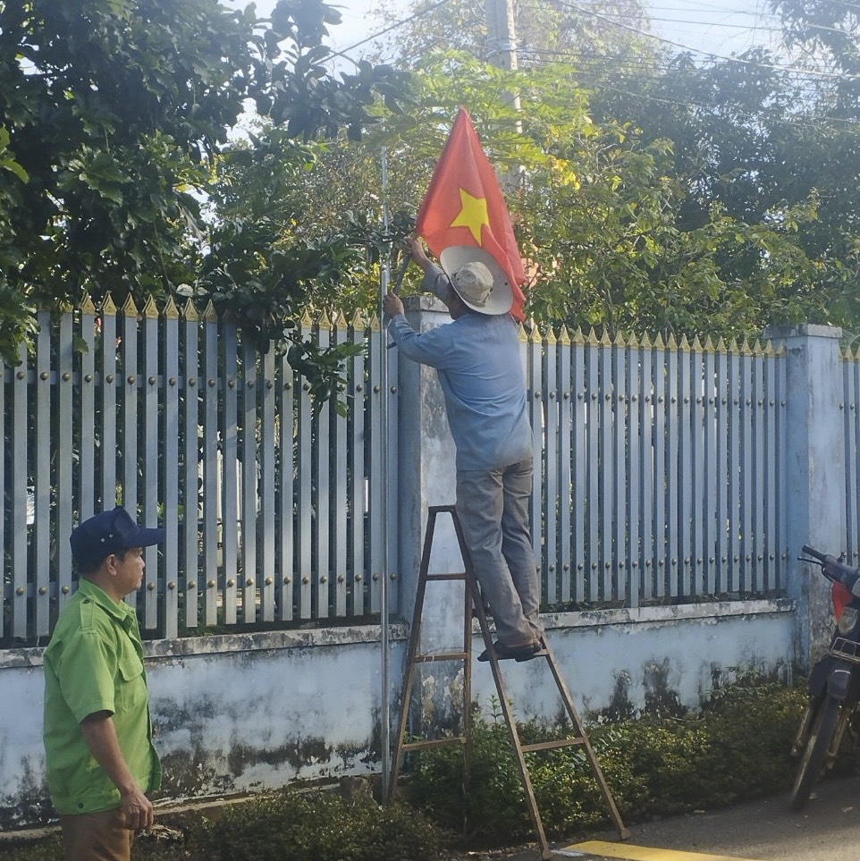 Người dân treo cờ tổ quốc chào mừng Ngày hội đại đoàn kết dân tộc.