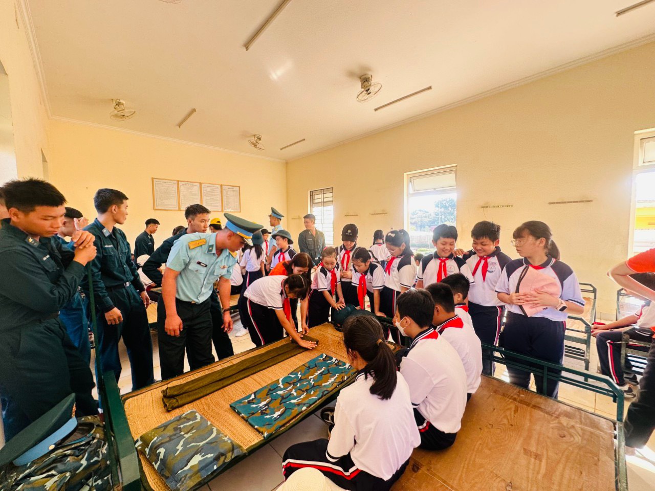 Học sinh trải nghiệm cách gấp chăn màn của bộ đội. 