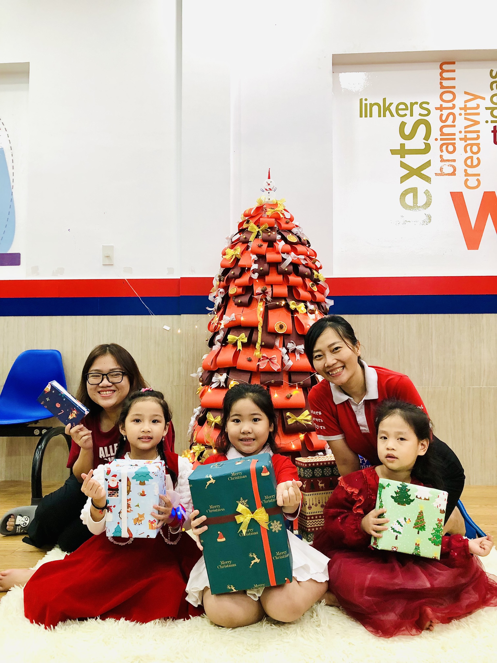 Nhân viên, học viên Trung tâm ngoại ngữ Phương Nam check-in bên cây thông Noel được làm thủ công bằng giấy màu sặc sỡ.