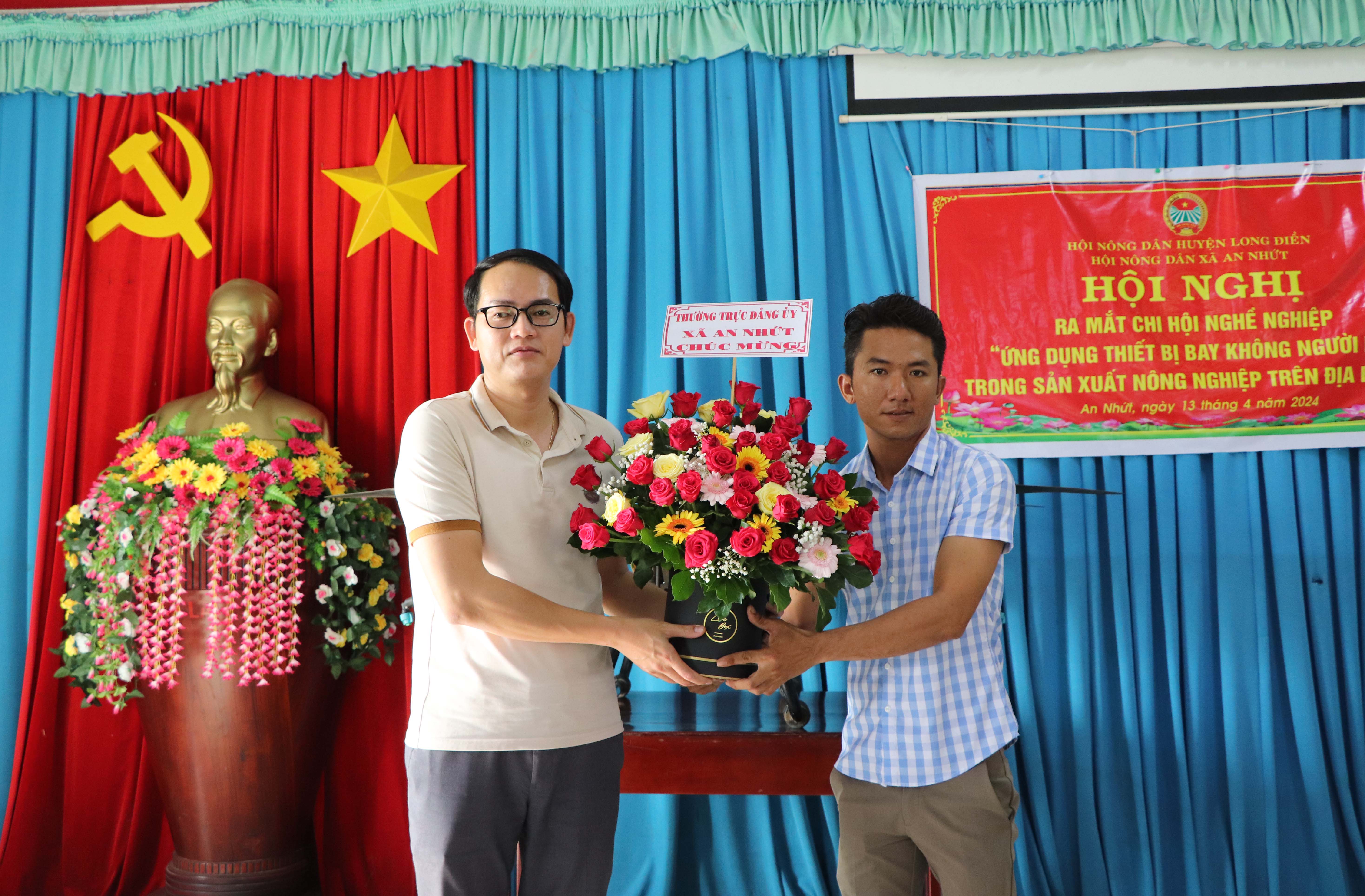 Ông Đỗ Minh Tân (bên trái), Bí thư Đảng ủy xã An Nhứt tặng hoa chúc mừng tại lễ ra mắt Chi hội Nông dân nghề nghiệp.