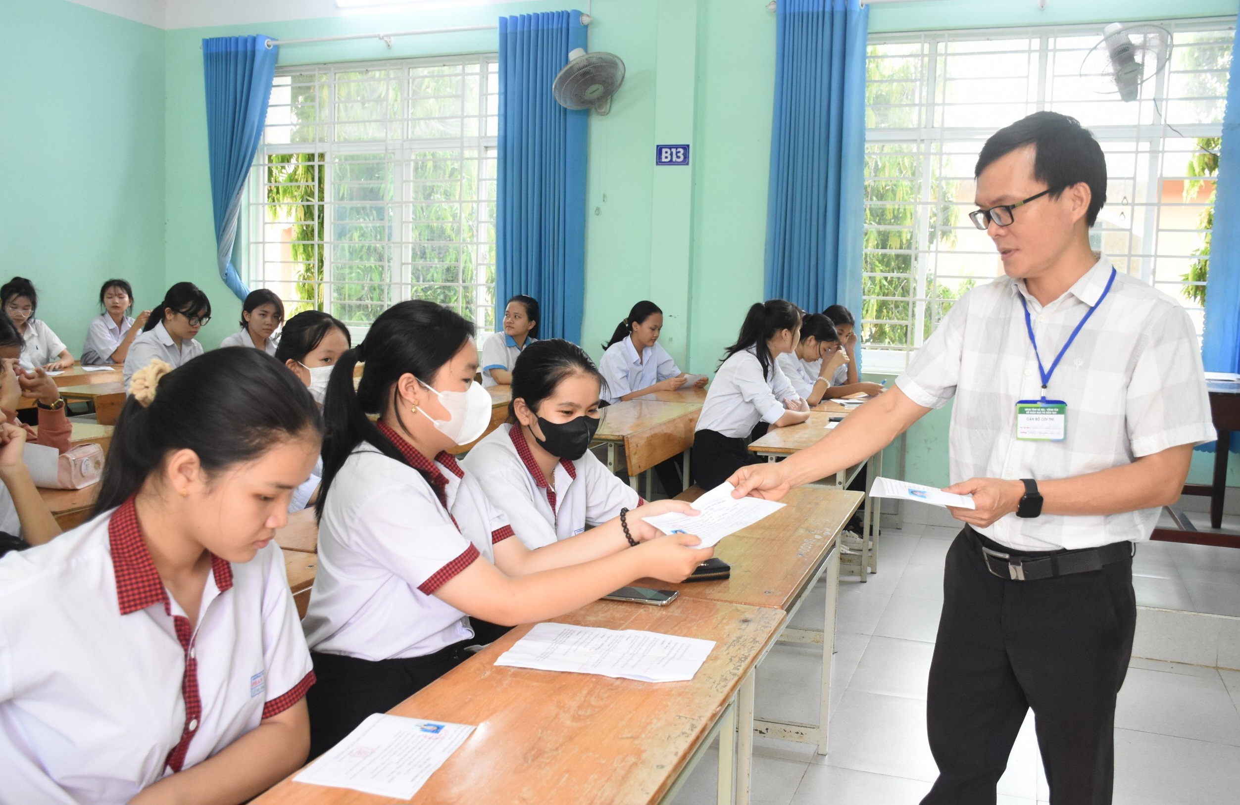 Cán bộ coi thi tại điểm thi THPT Nguyễn Du (huyện Châu Đức) phát thẻ dự thi để thí sinh kiểm tra, đối chiếu thông tin nhằm kịp thời đính chính khi phát hiện sai sót. Ảnh: NGỌC BÍCH