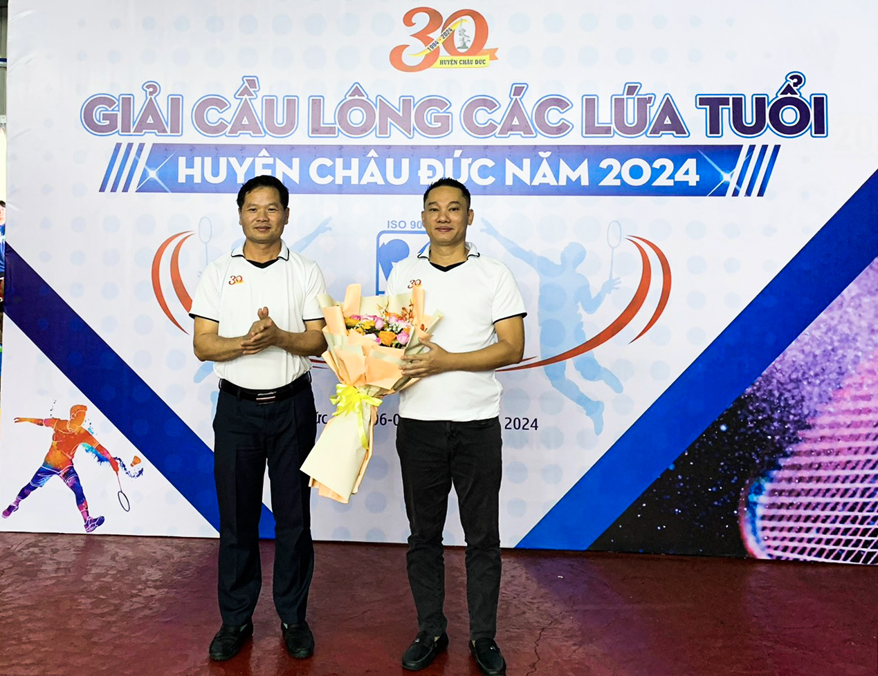 Ông Lê Thanh Liêm (bên trái), Phó Bí thư Thường trực Huyện ủy Châu Đức tặng hoa cho ông Trần Quốc Minh, Giám đốc Công ty TNHH Sản xuất - Thương mại Phúc Vinh, đơn vị tài trợ.