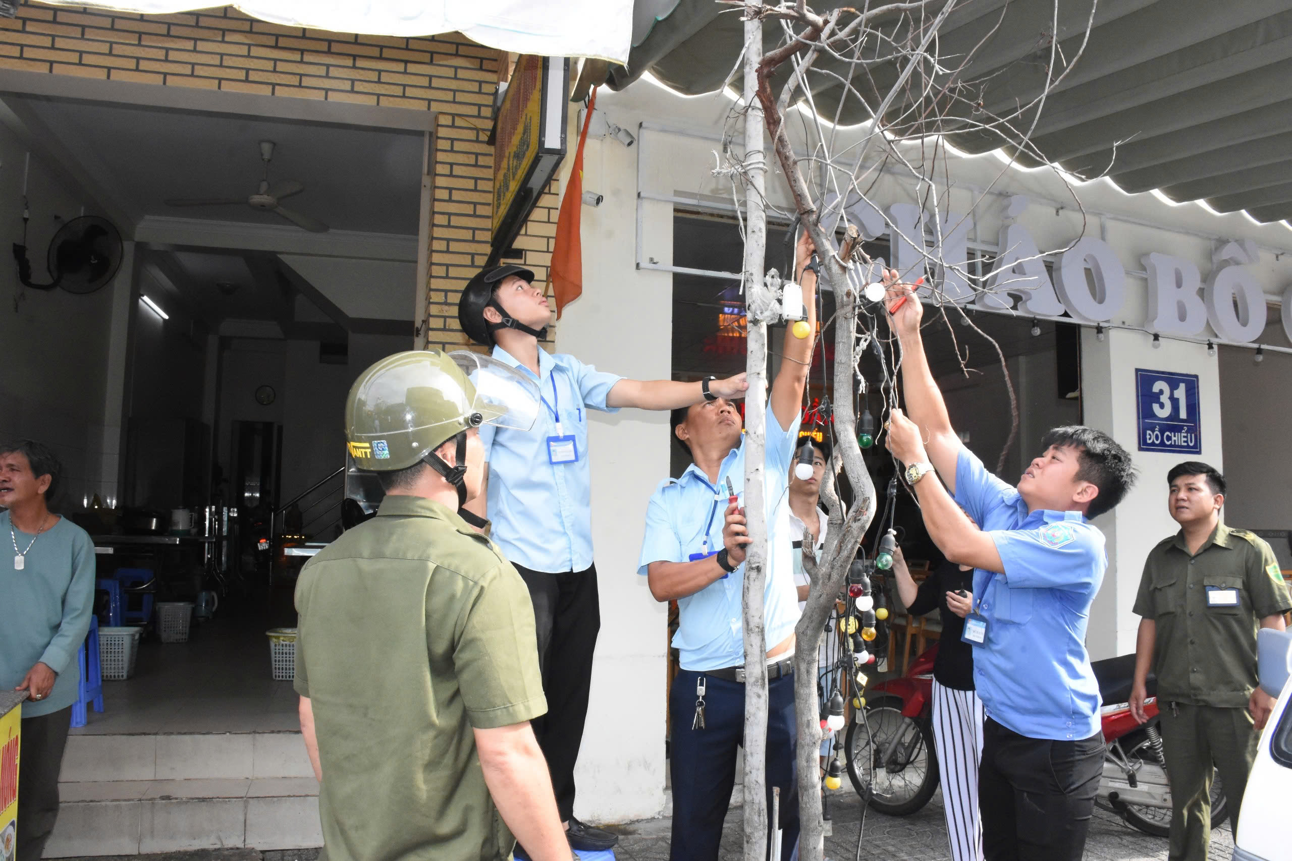Lực lượng chức năng phường 1 tháo gỡ các vật dụng người dân lấn chiếm để trang trí trên vỉa hè trước khu vực kinh doanh, buôn bán