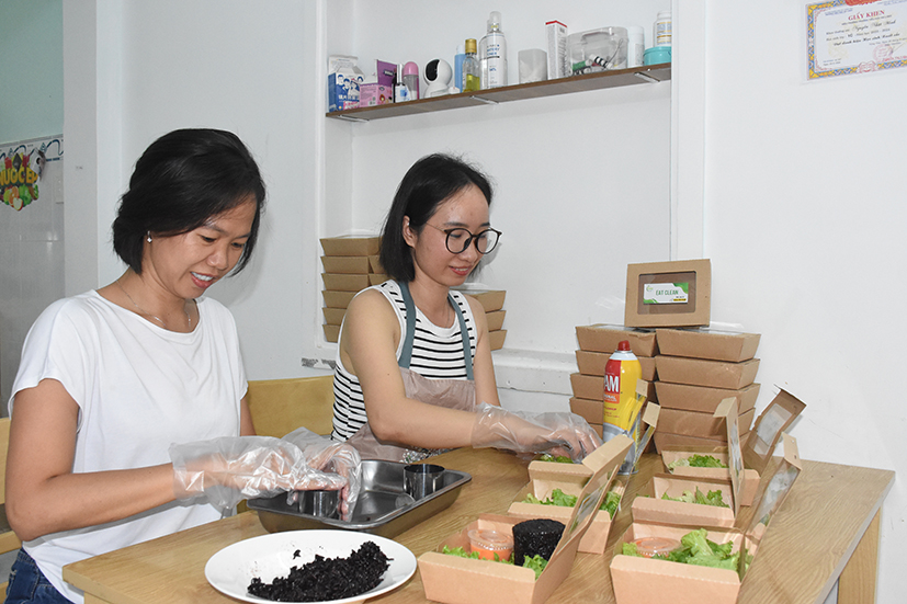 Chị Nguyễn Thị Duyên và chị Trần Thị Hạnh chuẩn bị các hộp thức ăn giao cho khách tại bếp Duyên Healthy.
