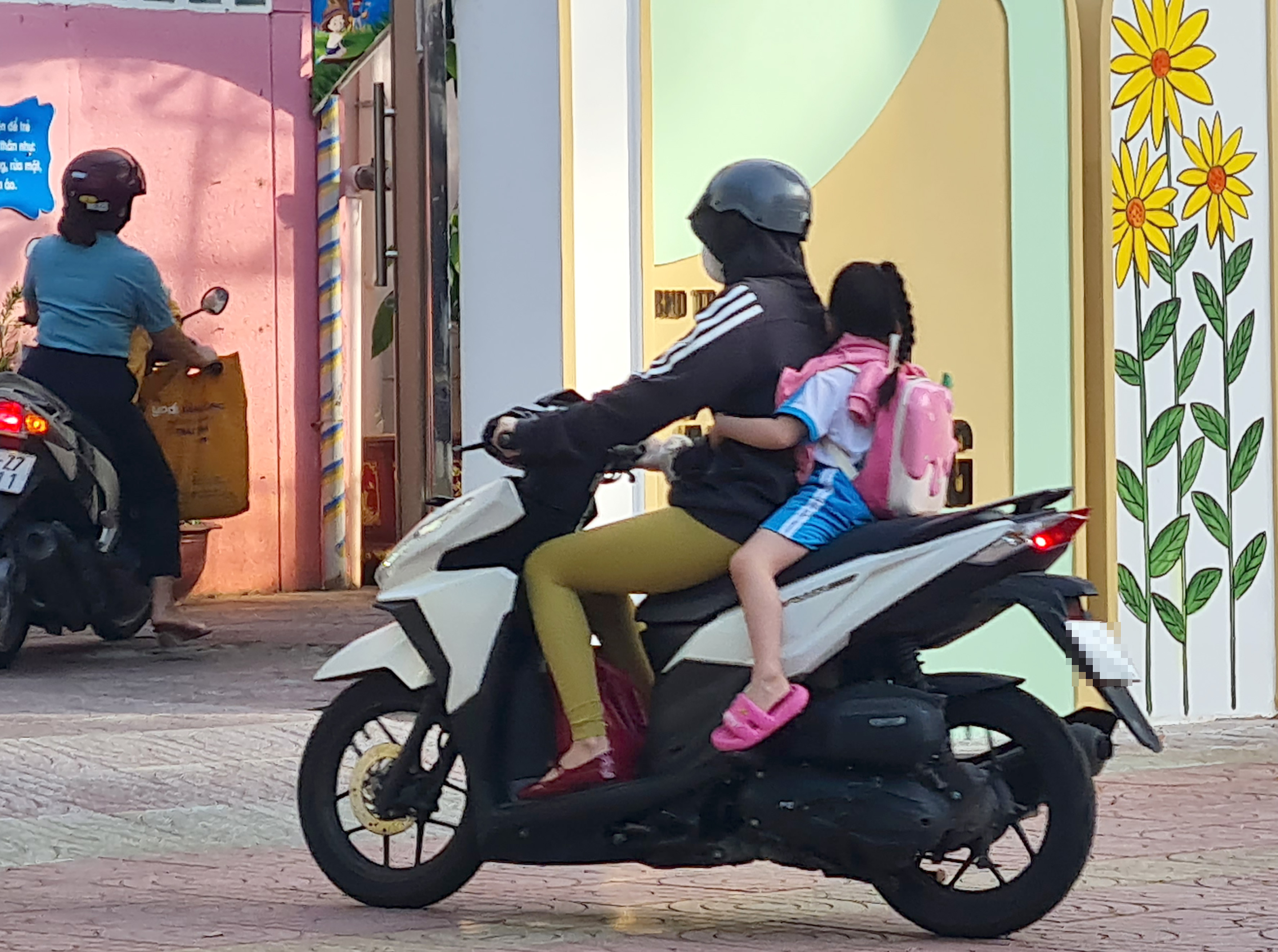 Dù pháp luật chưa quy định đội mũ bảo hiểm cho trẻ dưới 6 tuổi khi di chuyển bằng xe gắn máy đến trường,  tuy nhiên phụ huynh cần trang bị để bảo vệ cho con. Trong ảnh: Phụ huynh đưa con đến trường mầm non bằng xe gắn máy không trang bị mũ bao hiểm cho trẻ. (Ảnh chụp trên đường Nguyễn Du, TP.Vũng Tàu sáng ngày 01/11).