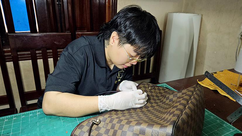 Anh Bảo Bảo chăm chú tỉ mỉ thay dây quai túi cho khách.