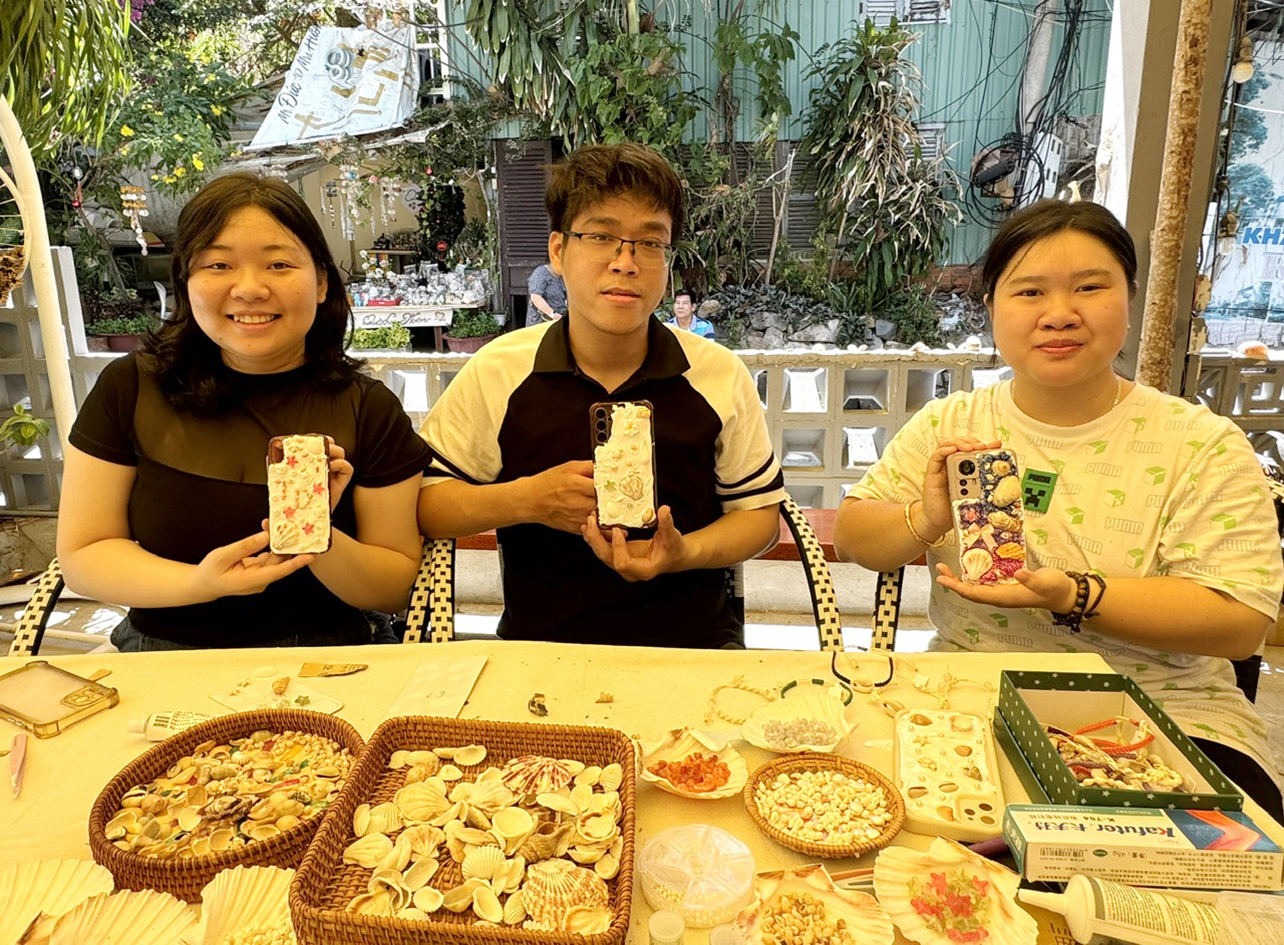 Chị Nguyễn Minh Thư (bìa phải) cùng các bạn khoe những chiếc ốp điện thoại mới sáng tạo từ vỏ sò, ốc .