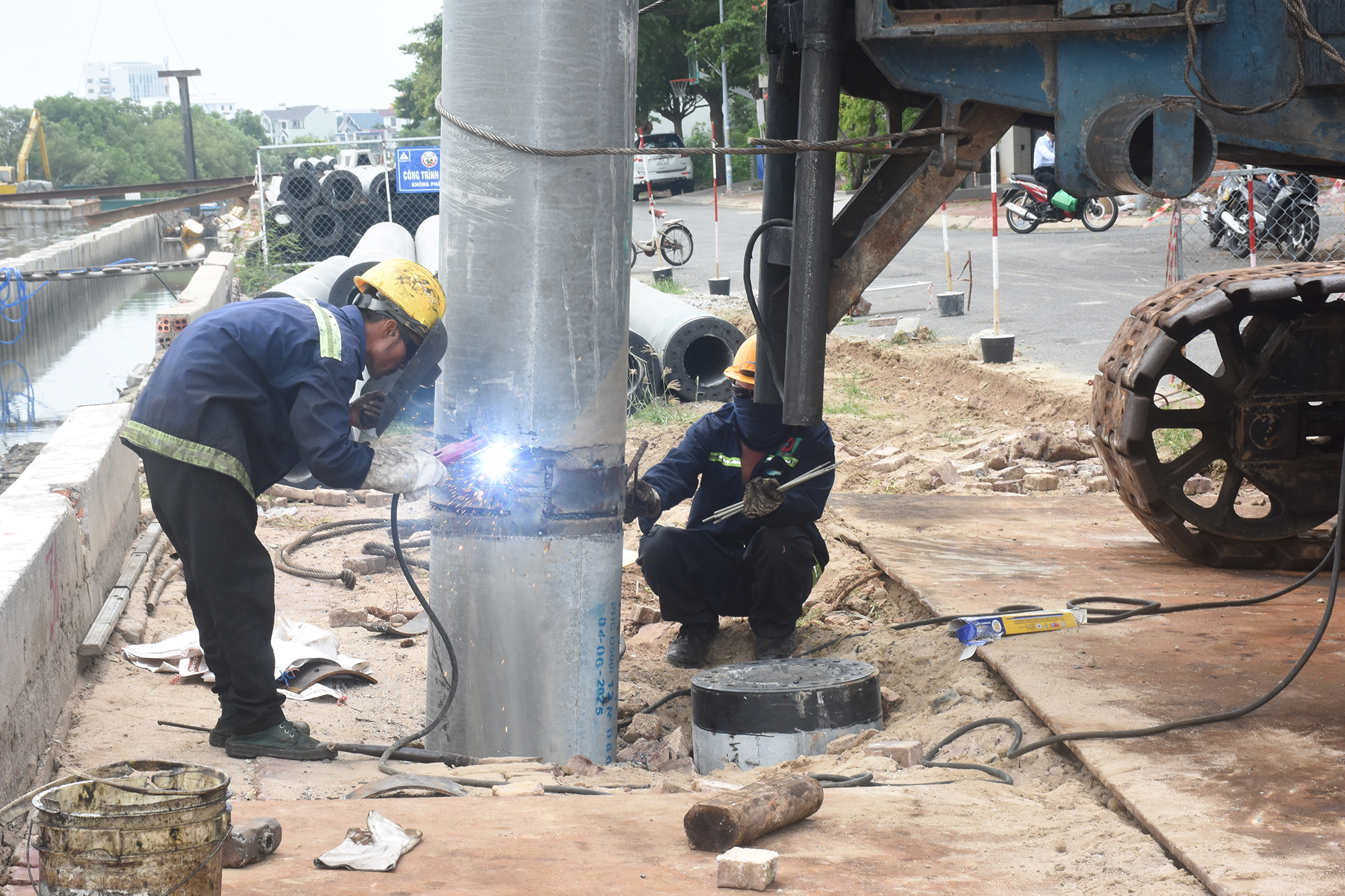 Đơn vị thi công xây đang thực hiện khoan dựng cọc lớn phần xây lắp kè dự án nạo vét kênh Bến Đình vào trưa 27-7. Ảnh: QUANG VŨ