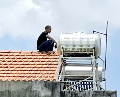 Đối tượng Duy Anh cầm dao len lên nóc nhà dân. 