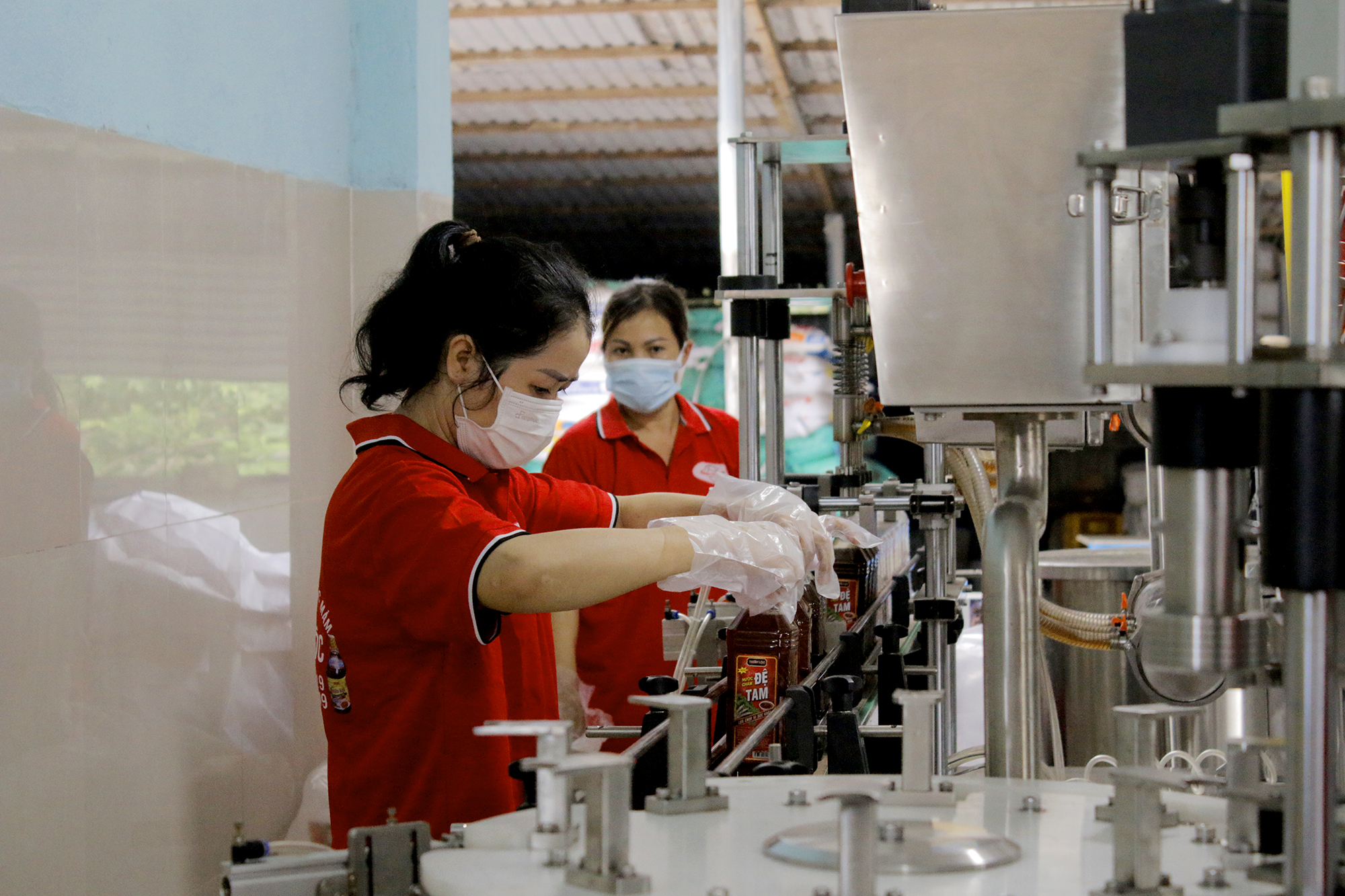 Công nhân Công ty TNHH sản xuất nước mắm Thiên Lộc, xã Hồ Tràm đóng chai nước mắm trên dây chuyền tại xưởng.