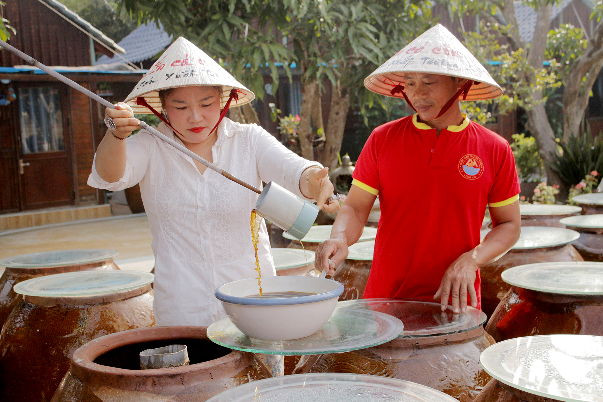 Chị Nguyễn Thị Chiến, Giám đốc Công ty TNHH sản xuất - Thương mại và Dịch vụ Hati, xã Phước Hải kiểm tra chất lượng nước mắm tại xưởng.