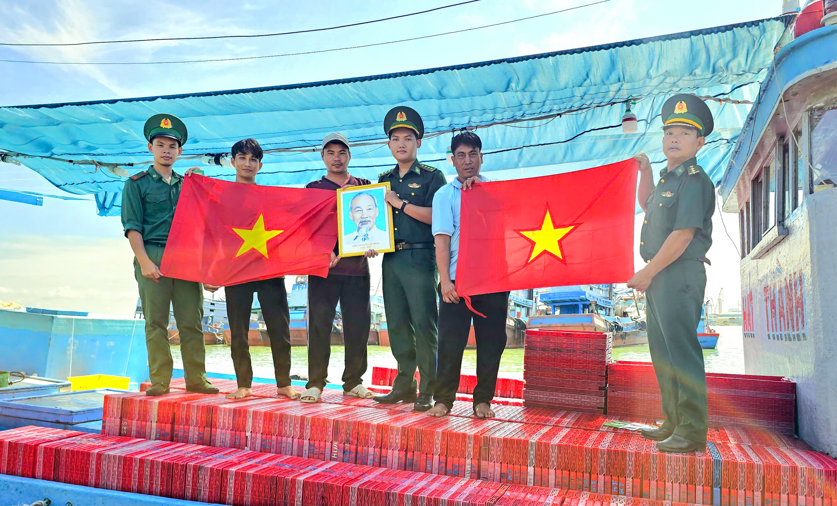 Cán bộ, chiến sĩ Đồn Biên phòng Bến Đá trao tặng cờ Tổ quốc và ảnh Bác Hồ cho ngư dân phường Vũng Tàu, TPHCM.